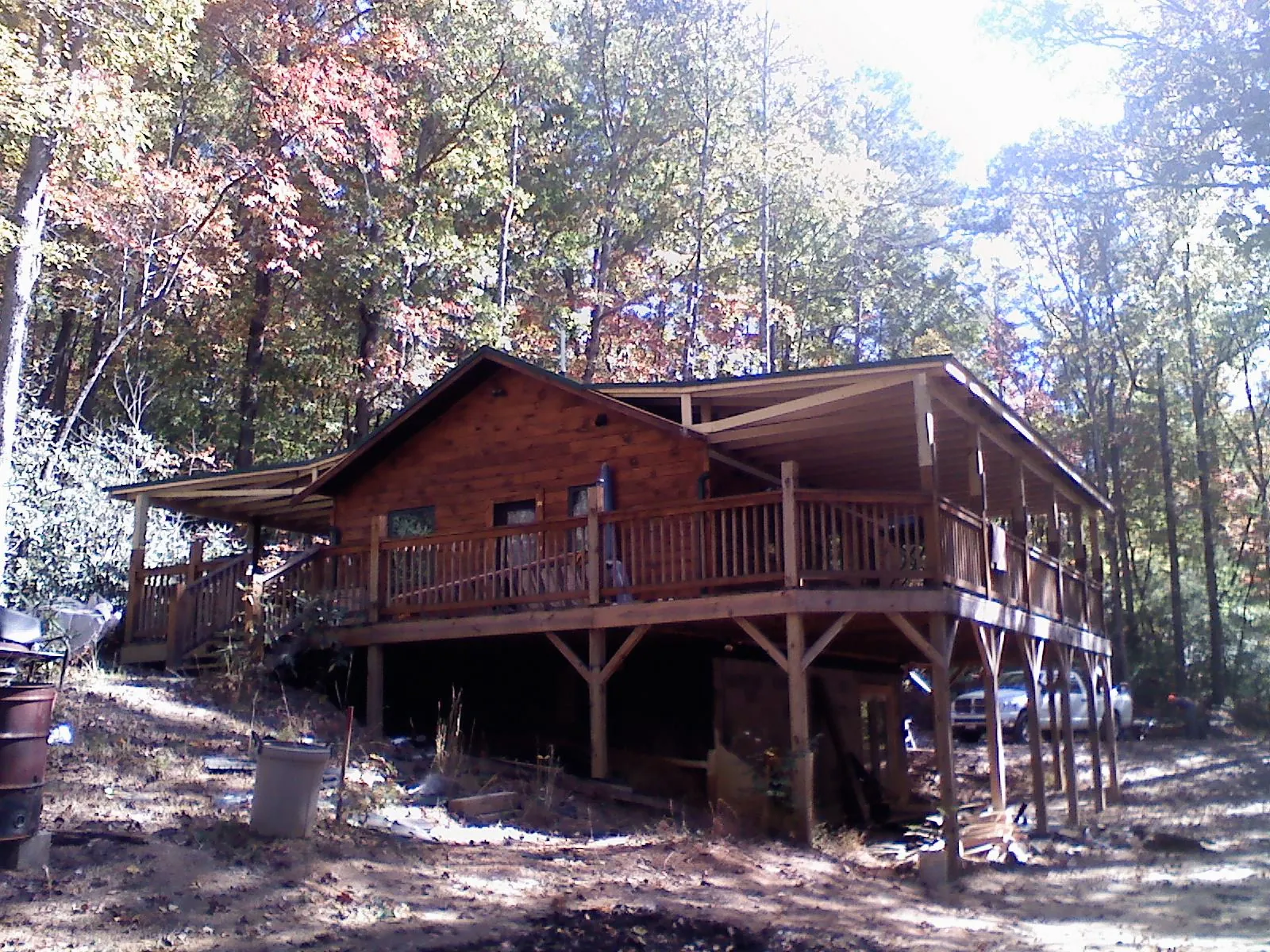 Log cabin with a wraparound porch and metal roof in the fall in Cresco