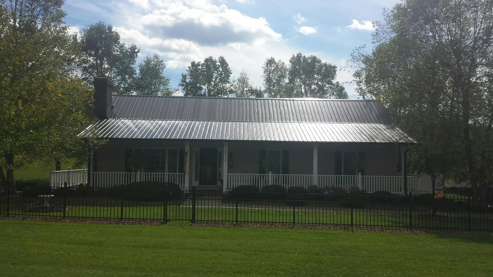 Gray metal roof on a brick ranch with a full width front porch — Gutter Guard Installation work by our crew in Cresco
